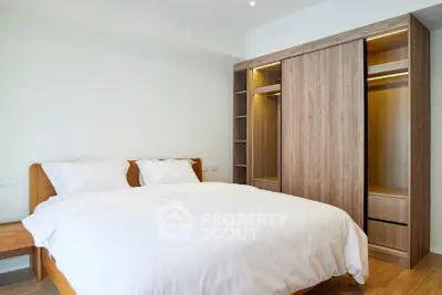 Modern bedroom with wooden wardrobe and cozy bed in bright apartment