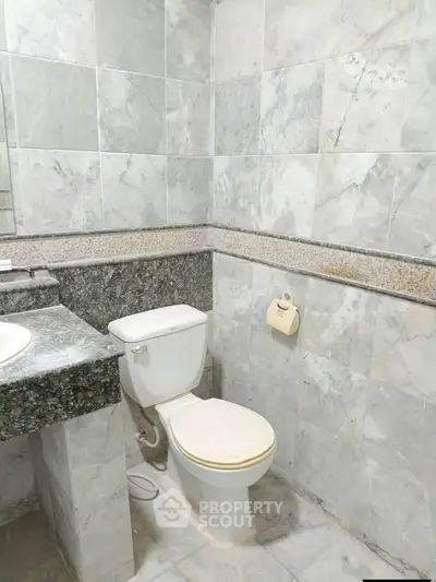 Elegant marble-tiled bathroom with modern fixtures and granite countertop.