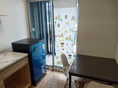 Cozy dining area with compact fridge and balcony view in modern apartment.