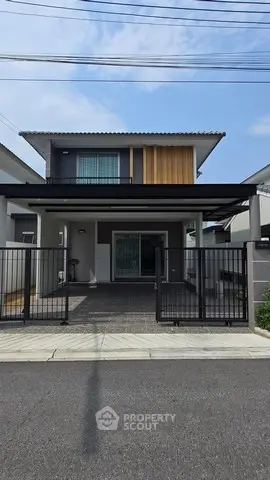 Modern two-story house with gated driveway and contemporary facade.