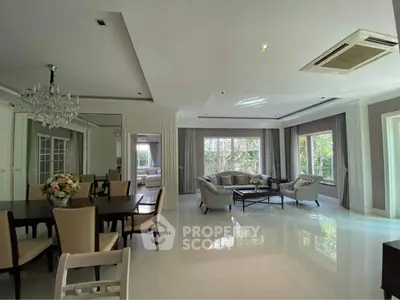 Spacious living room with elegant dining area and large windows offering garden views.