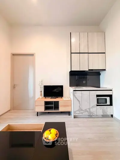 Modern minimalist living room with sleek kitchen area and stylish cabinetry.
