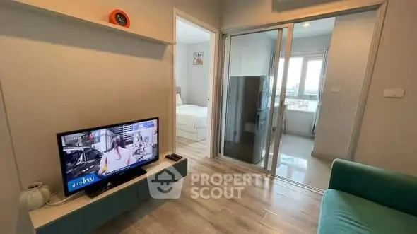 Modern living room with TV and sliding glass doors leading to bedroom and kitchen.