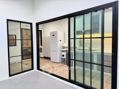 Modern kitchen with sleek appliances and open layout, featuring large glass doors for natural light.