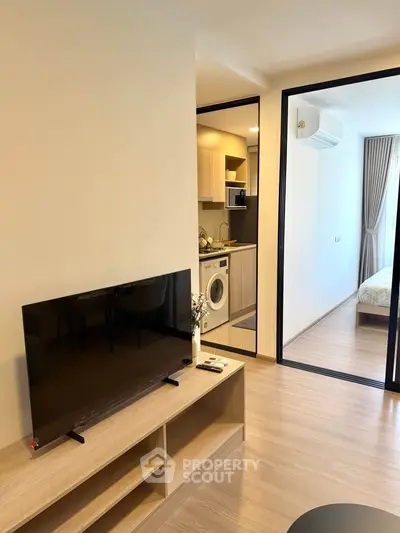 Modern apartment interior with TV, kitchen, and bedroom view