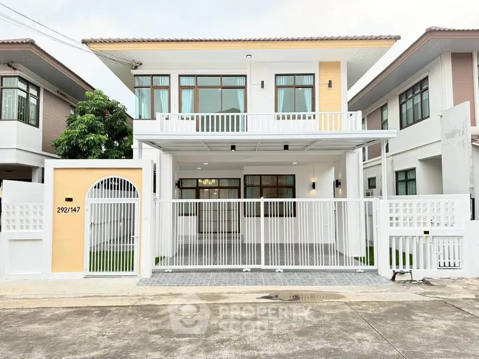 Modern two-story house with gated entrance and spacious balcony in a suburban neighborhood.