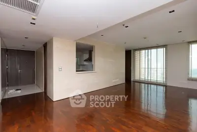 Spacious modern living room with hardwood floors and large windows in luxury apartment.
