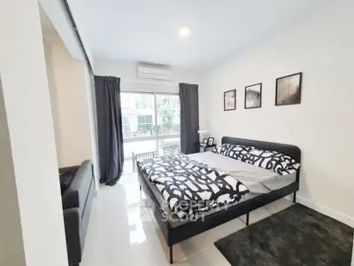 Modern bedroom with stylish decor and large window offering natural light in a contemporary apartment.