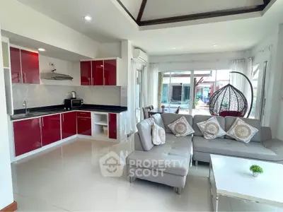 Modern open-layout living room with sleek kitchen, stylish red cabinets, and cozy seating area.