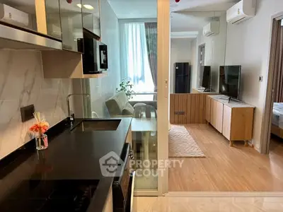Modern apartment interior with sleek kitchen and cozy living area, featuring stylish decor and natural light.