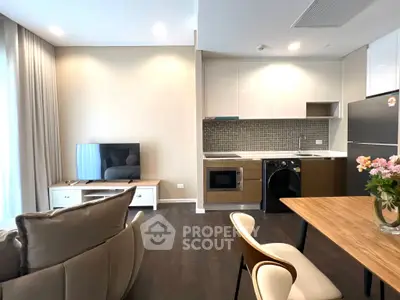 Modern open-layout living room and kitchen with sleek appliances and stylish decor.