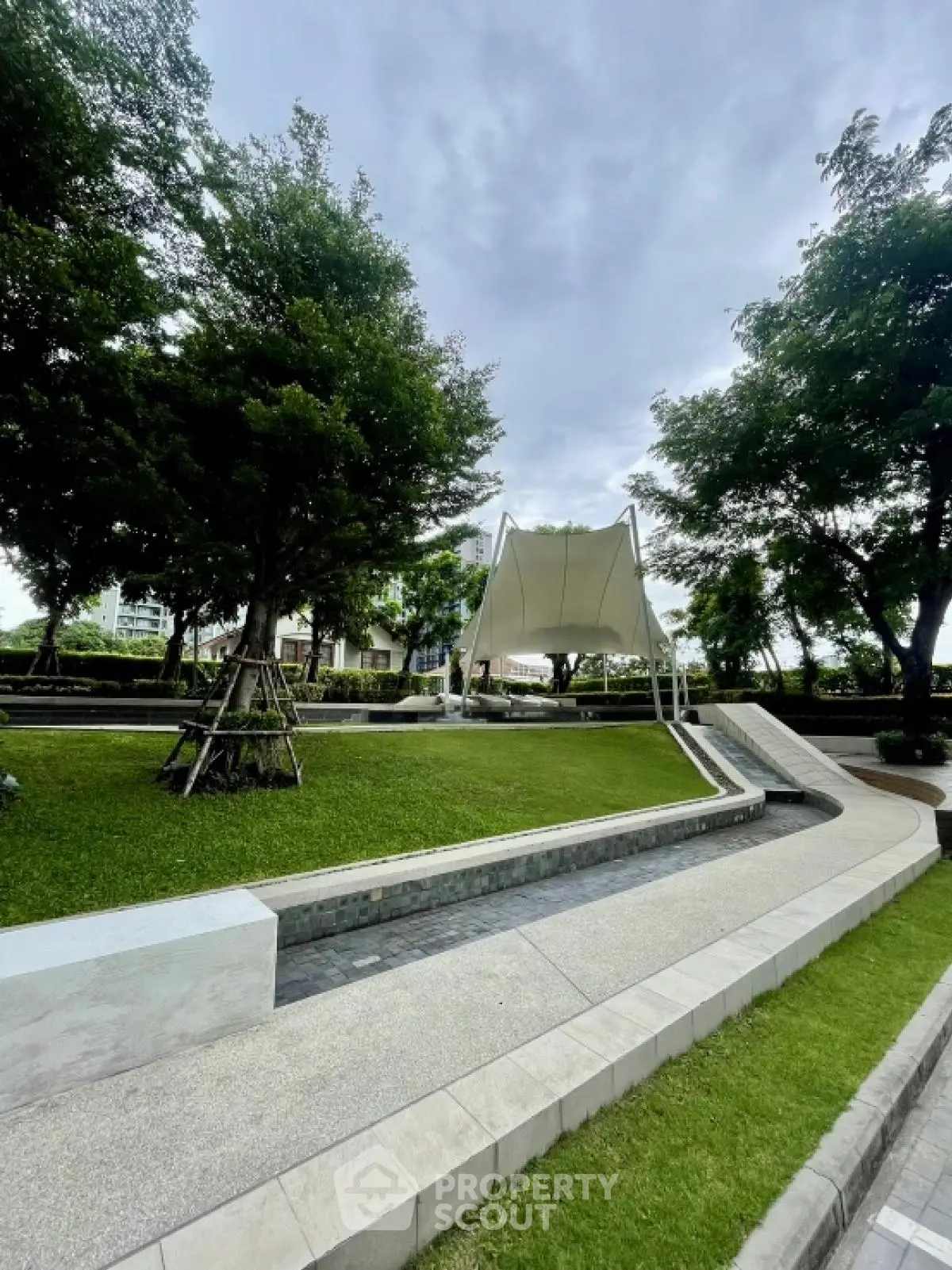 Beautiful garden with modern landscaping and shaded seating area in a residential complex.