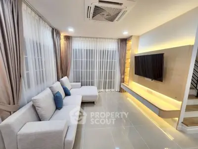 Modern living room with sleek design, featuring a large TV and cozy sectional sofa.