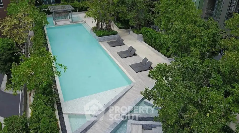 Luxurious outdoor pool area with lush greenery and modern lounge chairs in a serene setting.