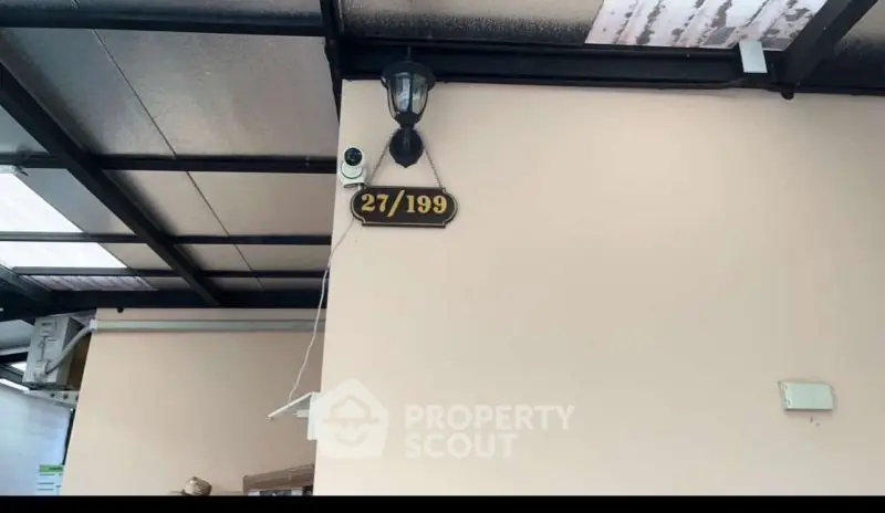 Covered outdoor area with security camera and house number signage