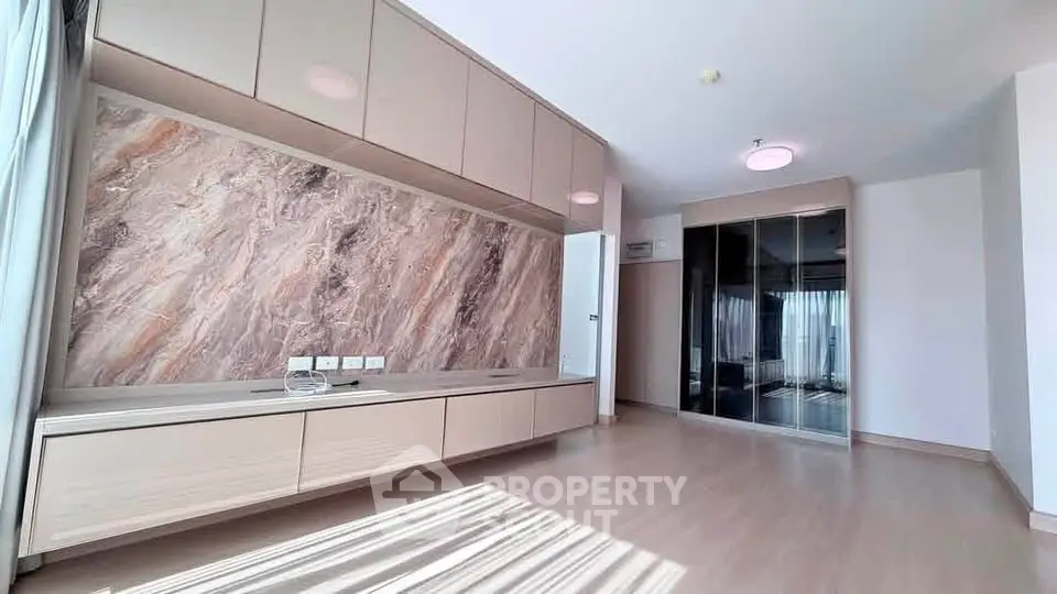 Spacious modern living room with elegant marble accent wall and ample natural light.