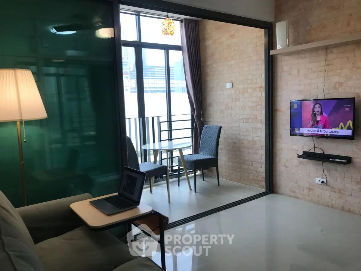 Modern living room with balcony view, featuring cozy seating and wall-mounted TV, perfect for relaxation.