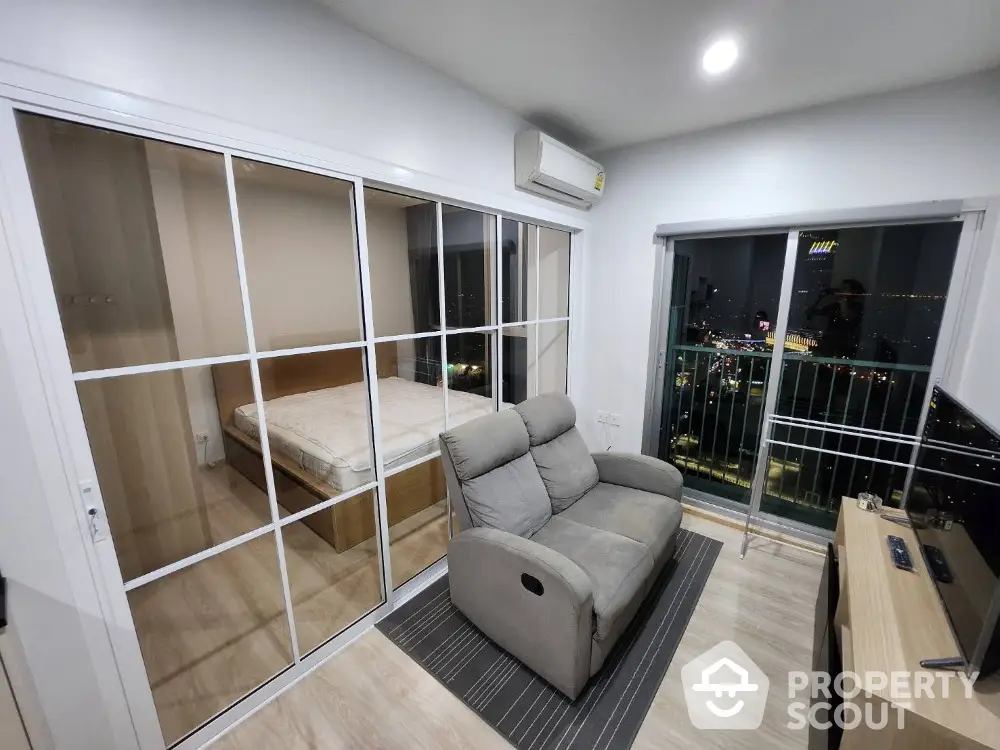 Modern apartment with glass partition, cozy living area, and city view balcony.