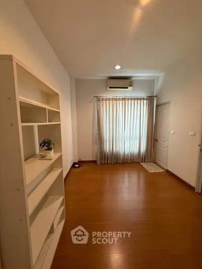 Spacious room with wooden flooring and natural light, perfect for versatile living space.