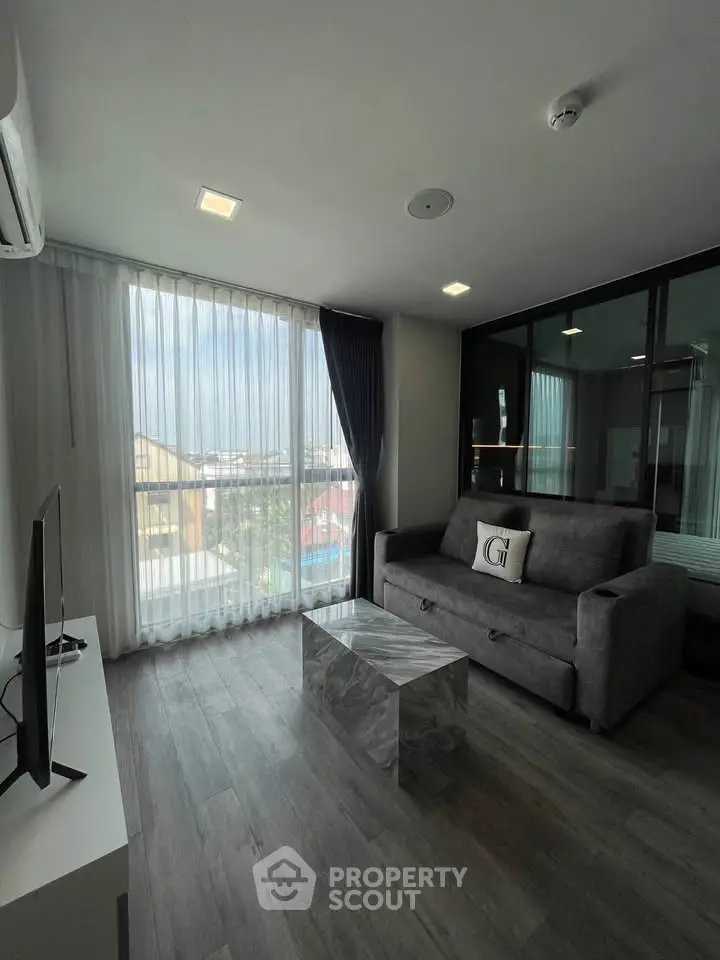 Modern living room with large window and stylish gray sofa