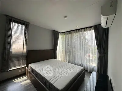 Spacious bedroom with large windows and modern decor in a luxury apartment.