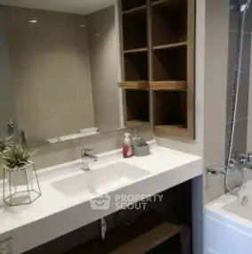 Modern bathroom with sleek sink and bathtub in stylish apartment.