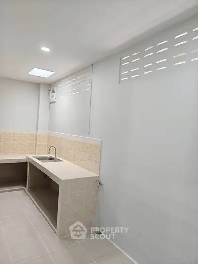 Spacious kitchen with tiled countertops and ample lighting, perfect for culinary enthusiasts.