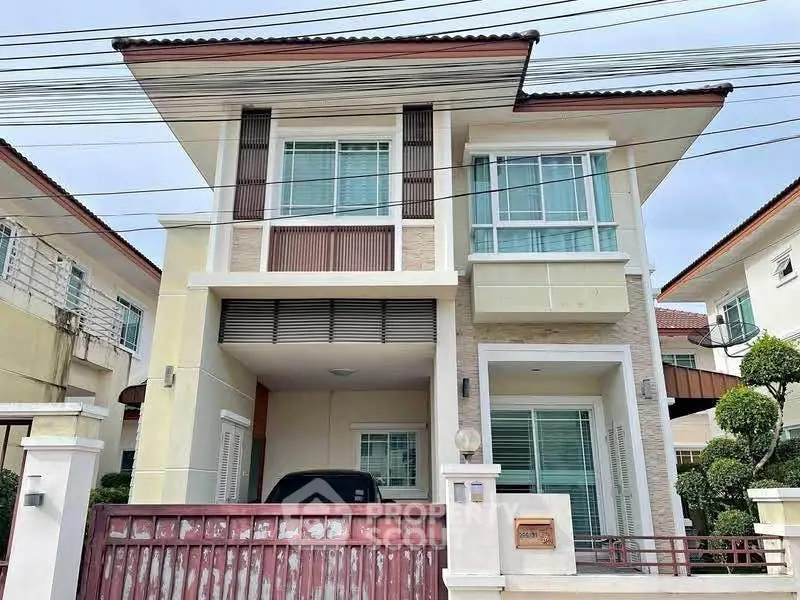 Modern two-story house with a gated entrance and large windows, perfect for family living.
