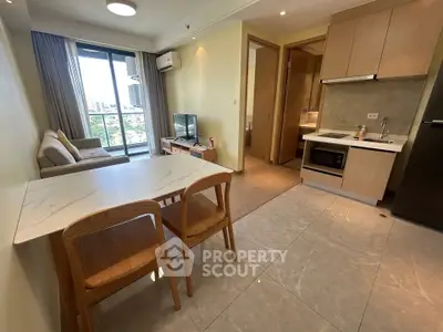 Modern open-layout living room with kitchen, featuring a balcony with city view, perfect for urban living.