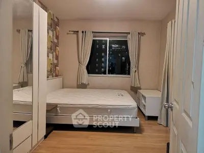Cozy bedroom with modern decor and large window offering city view, perfect for urban living.