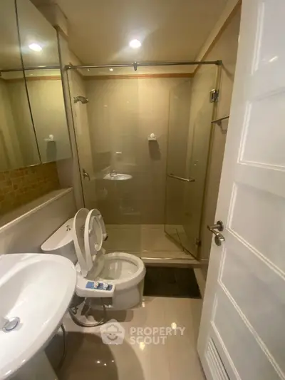 Modern bathroom with glass shower enclosure and sleek fixtures in a contemporary apartment.