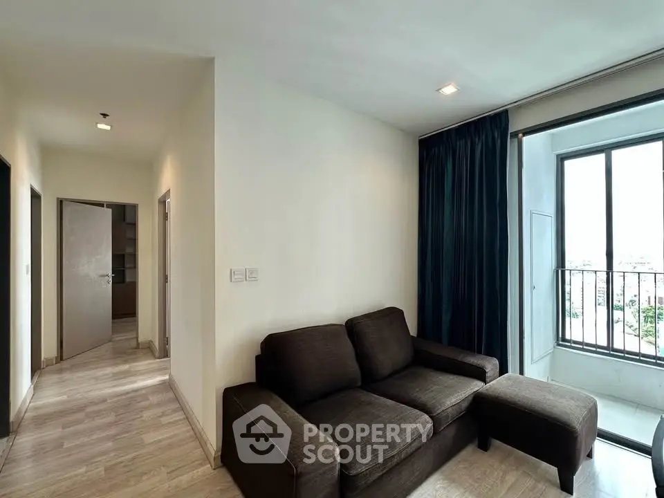 Modern living room with dark sofa and balcony view in a bright apartment