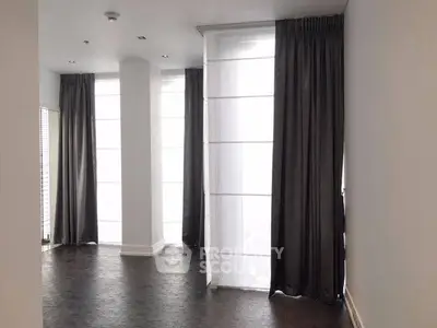 Spacious modern living room with floor-to-ceiling windows and elegant dark curtains.
