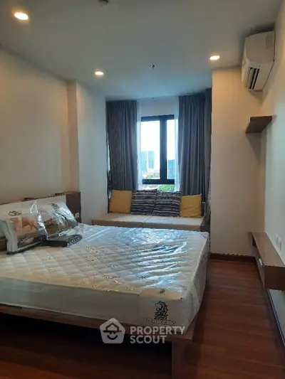 Cozy bedroom with large window and modern furnishings in a stylish apartment.