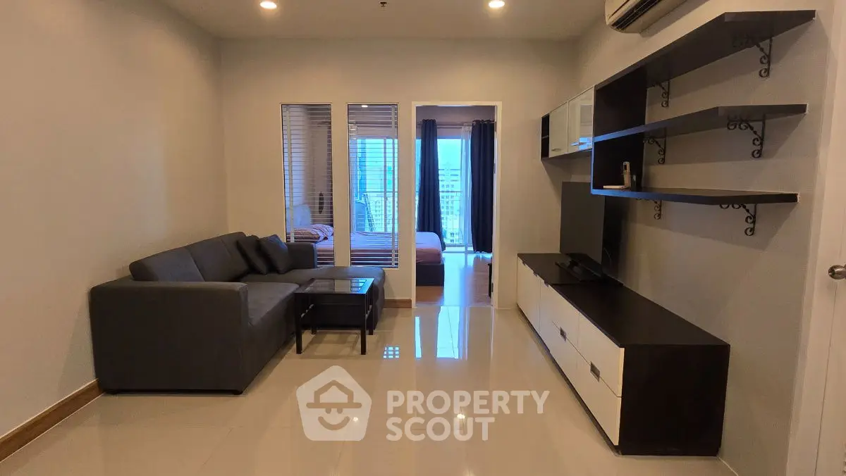 Modern living room with sleek furniture and open view to bedroom, perfect for urban living.