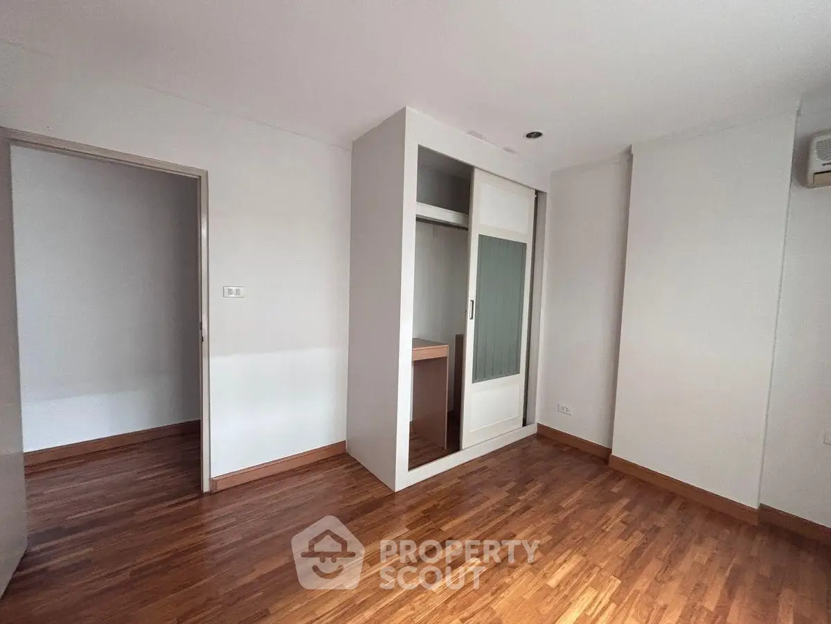Spacious bedroom with wooden flooring and built-in wardrobe