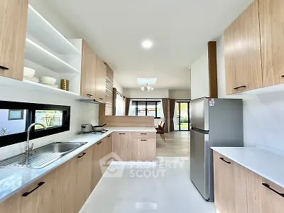 Modern kitchen with sleek wooden cabinets and stainless steel appliances in open layout.