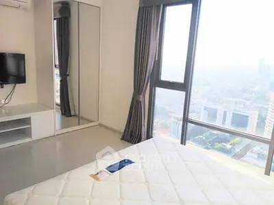 Bright bedroom with large window offering stunning city views, modern furnishings, and ample natural light.