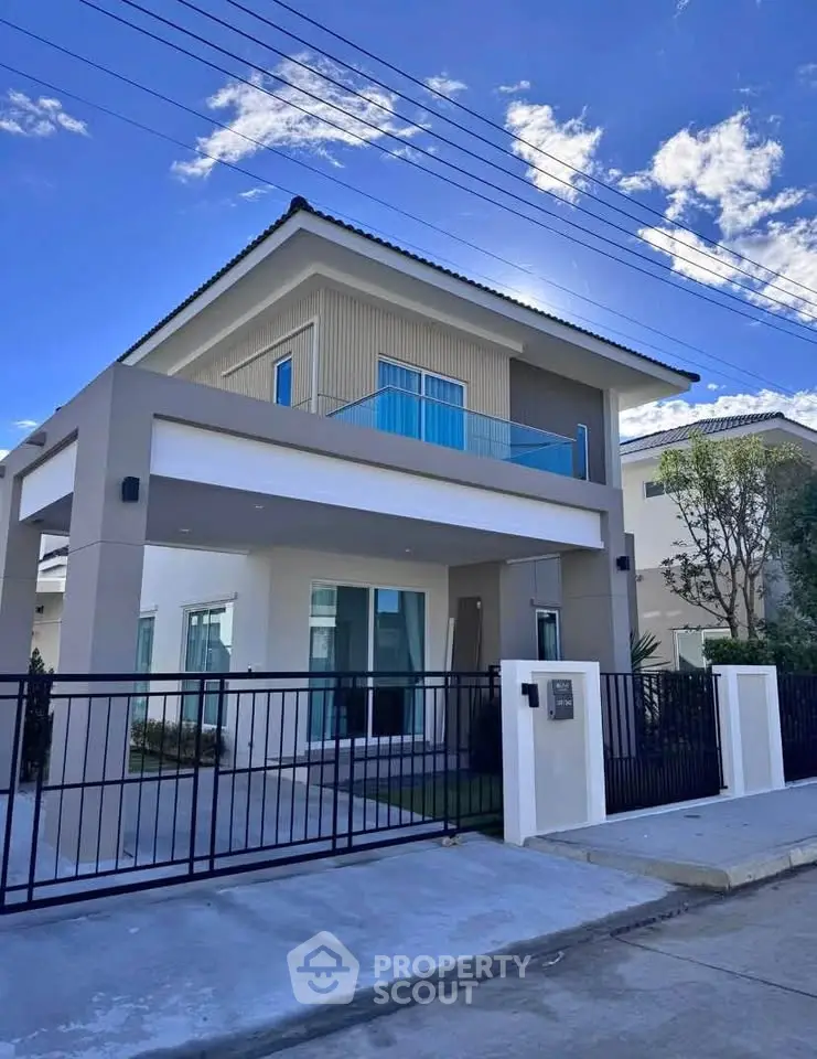 Modern two-story house with sleek design and spacious balcony under a clear blue sky.