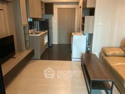 Modern apartment interior with compact kitchen and living area featuring sleek furniture and appliances.