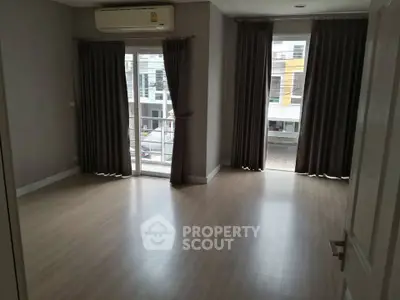 Spacious empty room with large windows and wooden flooring, perfect for customization.