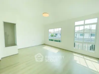 Spacious sunlit living room with large windows and modern flooring