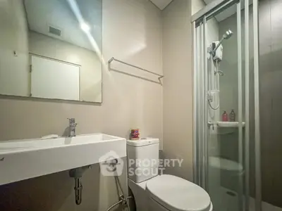 Modern bathroom with sleek fixtures and glass shower enclosure.