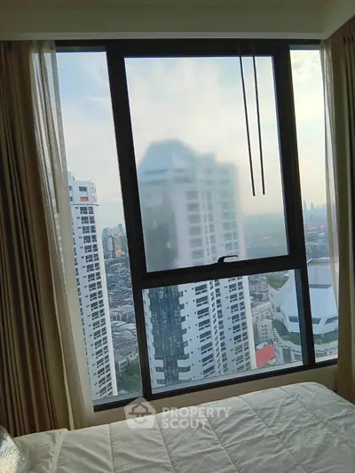 Stunning city view from a high-rise bedroom window, showcasing urban skyline and modern architecture.