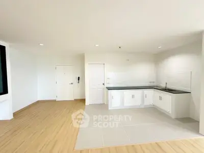 Spacious open-plan kitchen with sleek white cabinetry and modern flooring