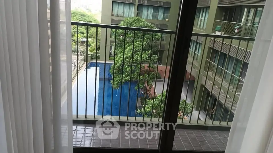 Modern apartment balcony with pool view and lush greenery