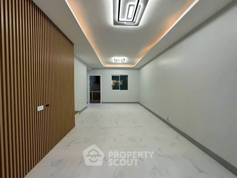 Modern minimalist living room with sleek lighting and wooden accent wall