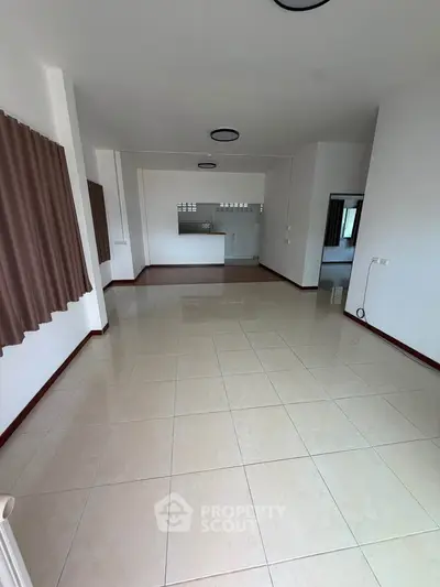 Spacious open-plan living area with tiled flooring and large windows, perfect for modern living.