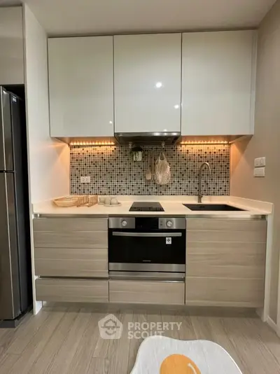 Modern kitchen with sleek cabinetry and built-in oven, featuring stylish backsplash and under-cabinet lighting.