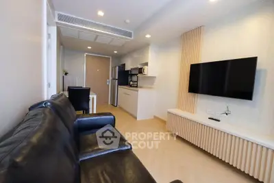 Modern living room with sleek black leather sofa and wall-mounted TV in stylish apartment.